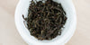 A top-down photo of brewed Phoenix oolong tea leaves in a gaiwan.